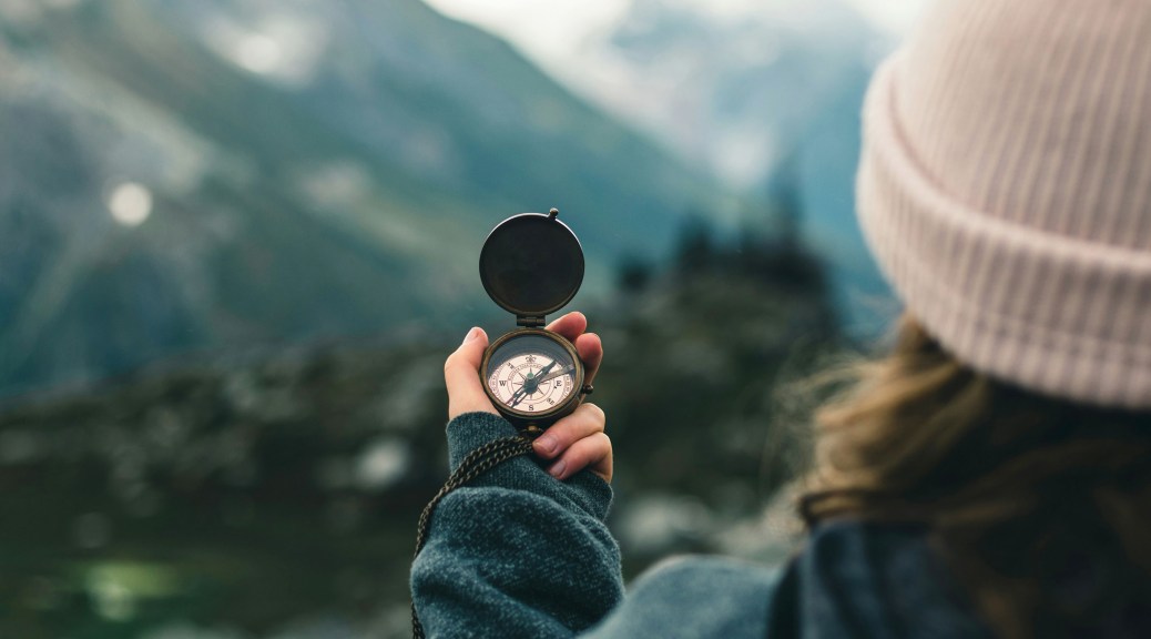 Three additional benefits of the growing trend of women leaders | This photo shows a woman holding up a compass in a mountainous area